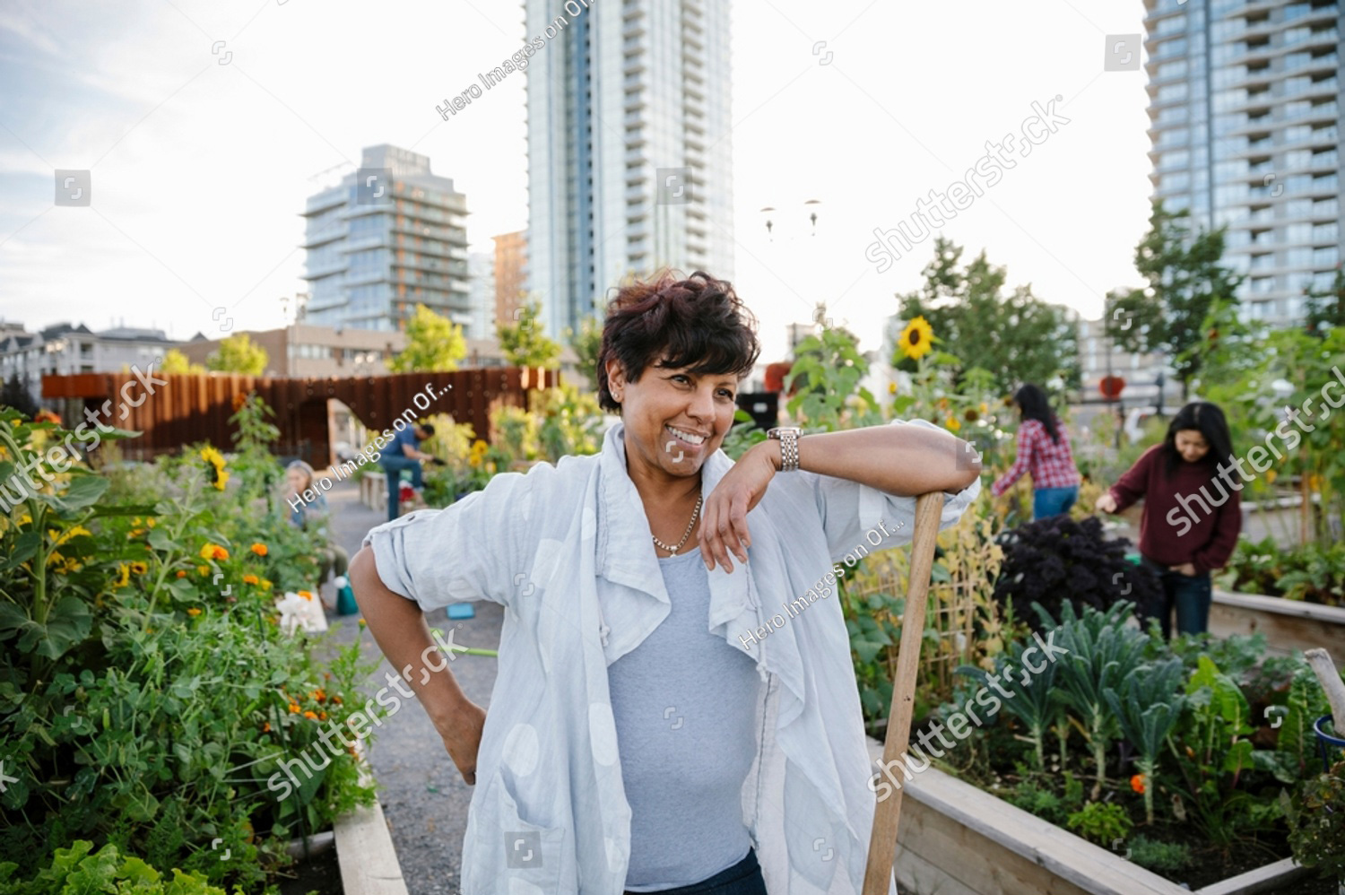portrait of a happy carefree mature woman gardening in urban community garden
